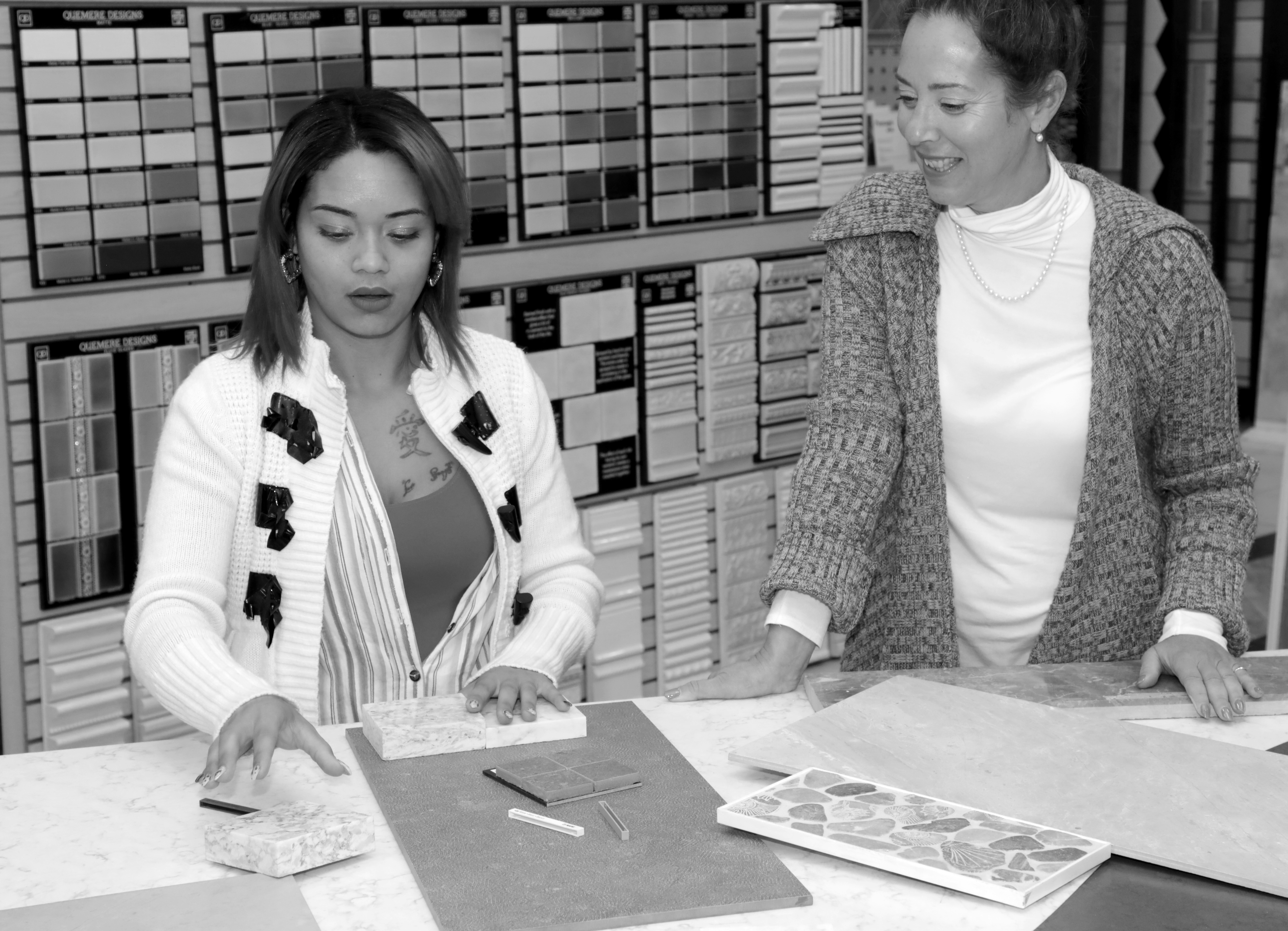 Two women examining stone and tile samples in various colors.