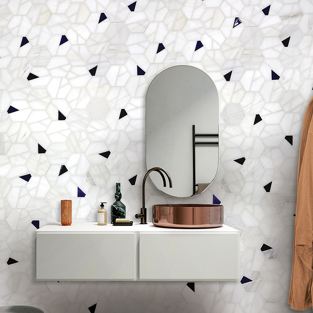 White hexagonal tiles with black accents on a wall behind a modern sink and mirror.
