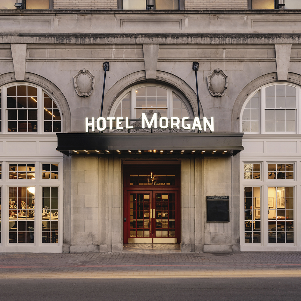 Entrance of Hotel Morgan with beige stone facade and red double doors.