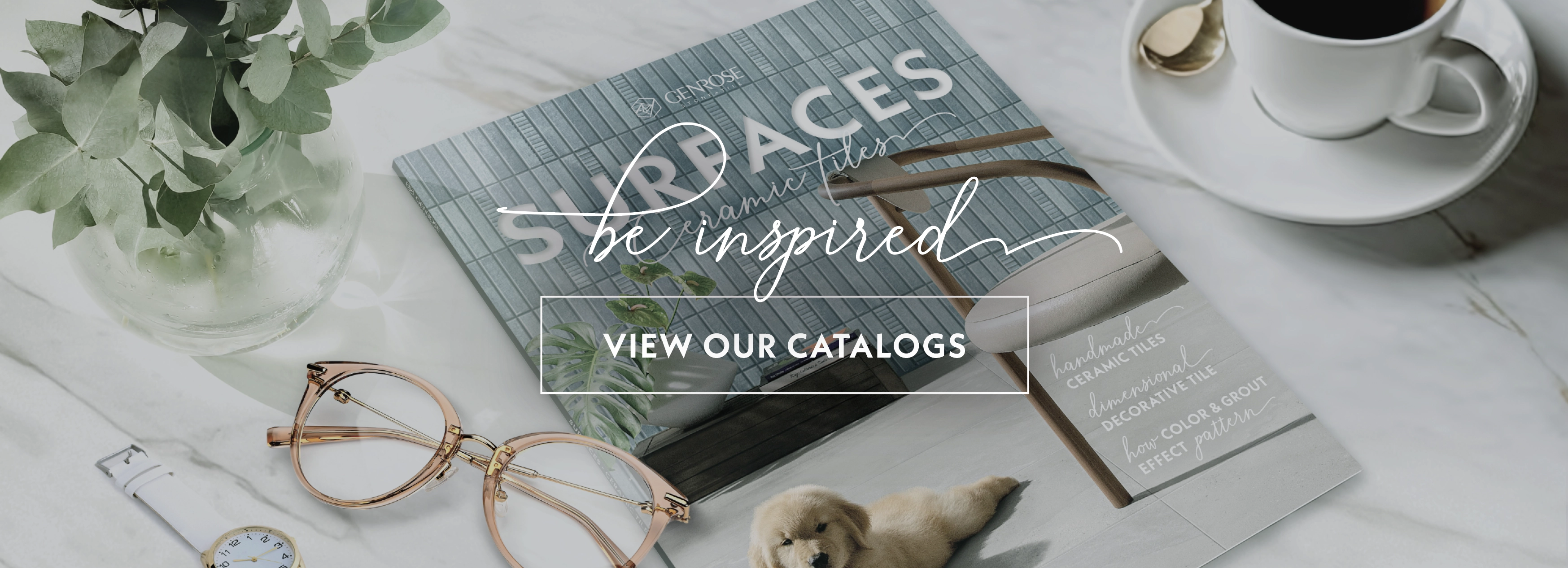 Catalog with blue and gray tiles, glasses, plant, and coffee cup.