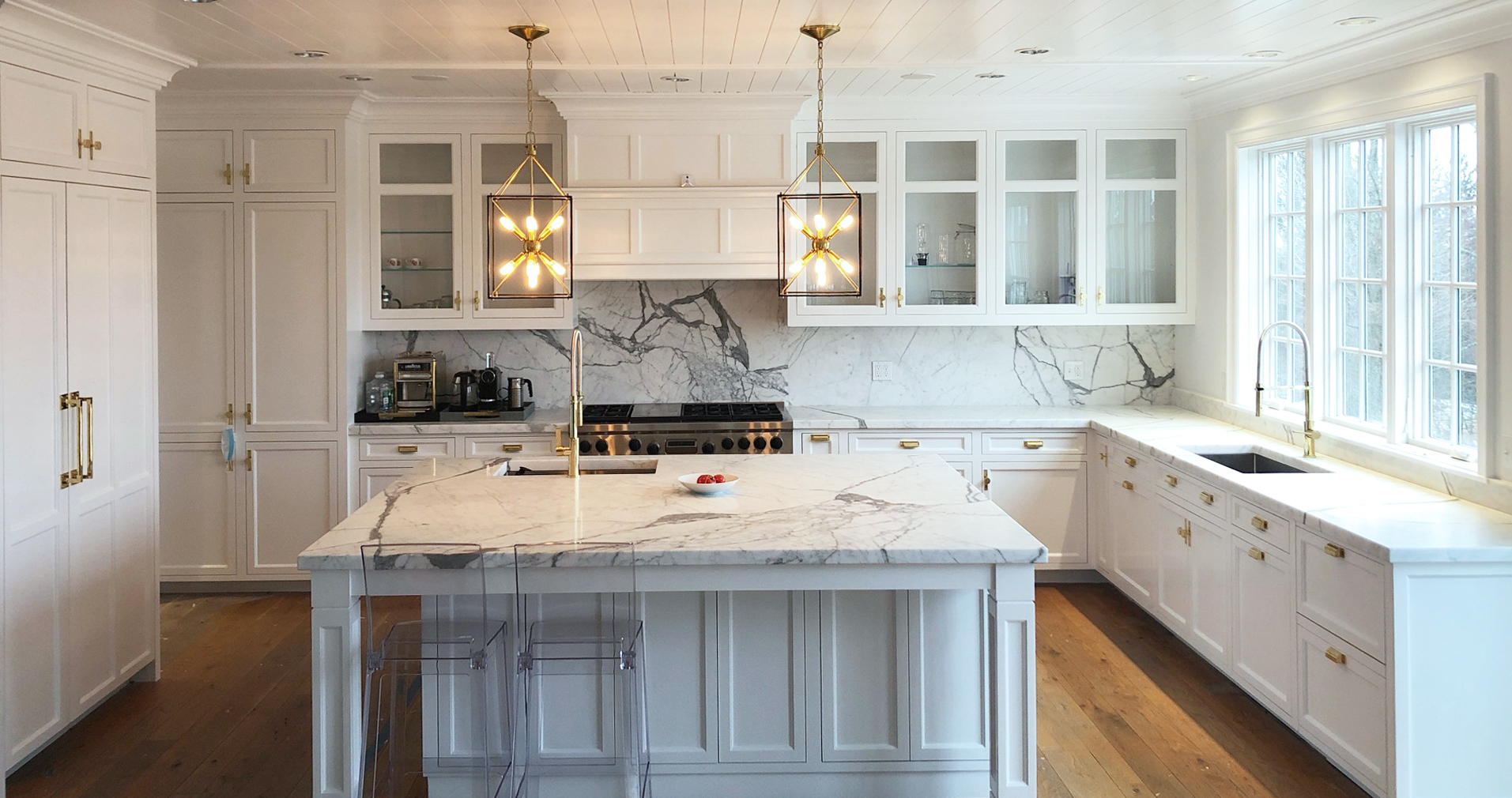 Modern kitchen with white cabinets, marble countertops, and a marble backsplash.